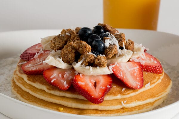 A plate of pancakes with strawberries and blueberries.
