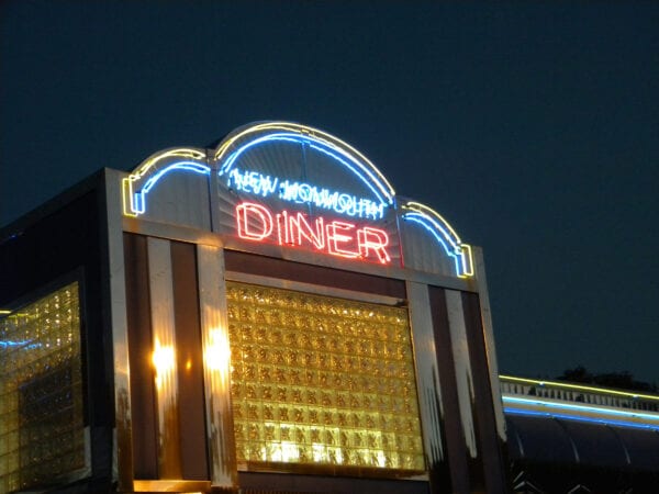 A neon sign lit up at night in front of the diner.
